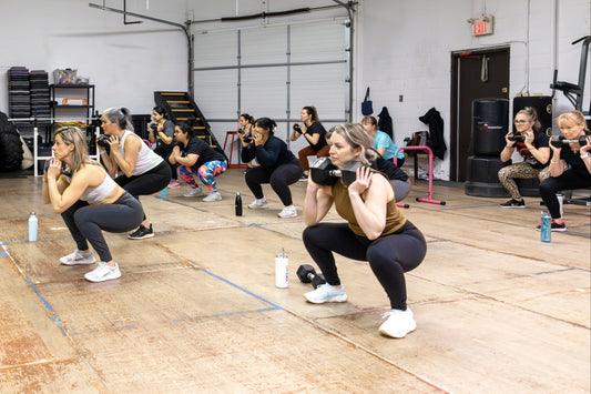 Group of people exercising in a gym with weights and exercise mats on the floor.